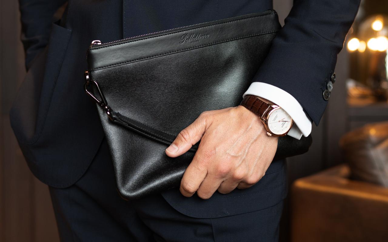 Stilvolles Herren Outfit mit schwarzer Leder Tasche, Mann im Anzug kombiniert die Pouch als modernes Business-Accessoire.