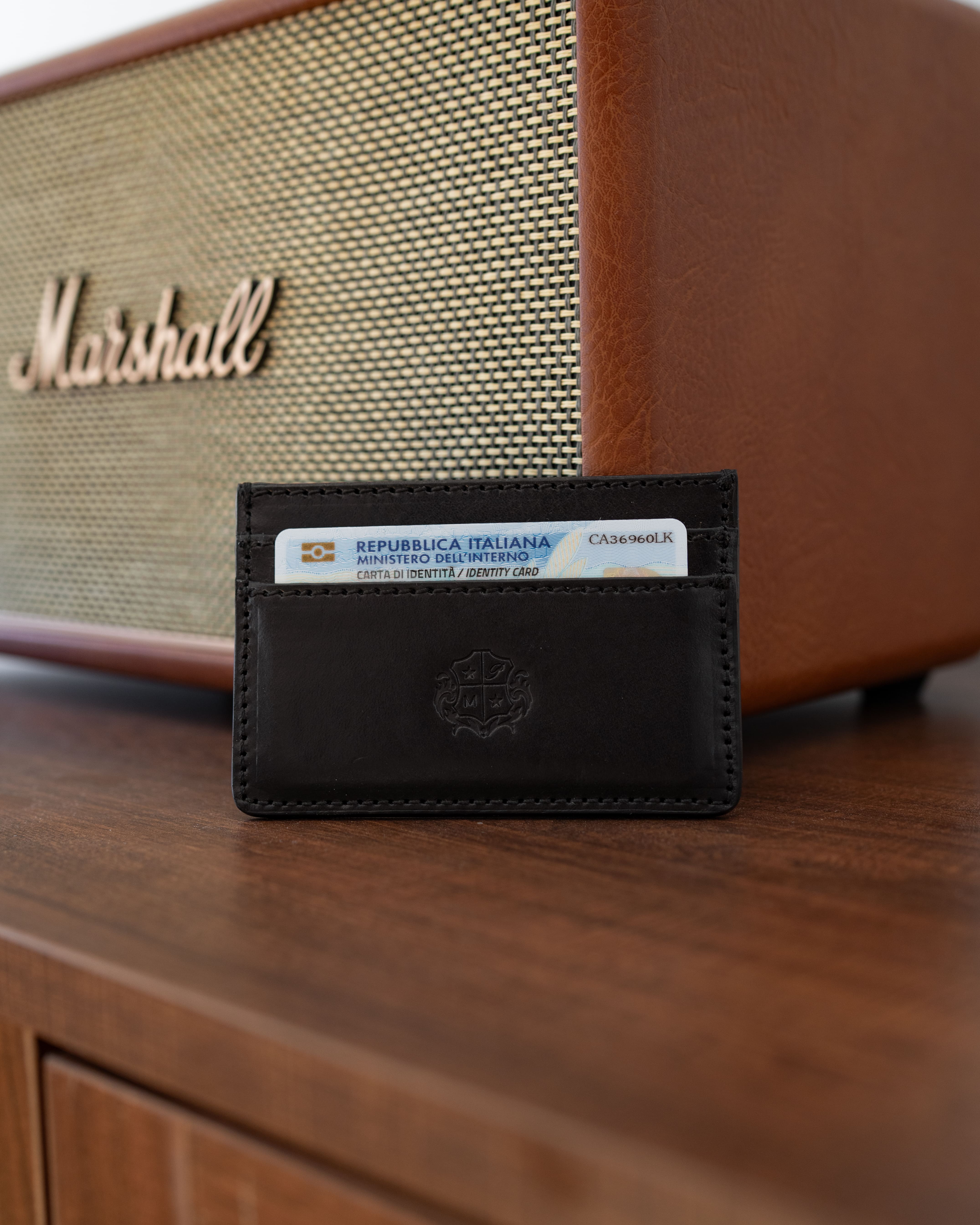 Handgenähter Cardholder aus schwarzem Leder in der Hand eines Mannes, ultraflaches Portmonee für minimalen Platzbedarf.
